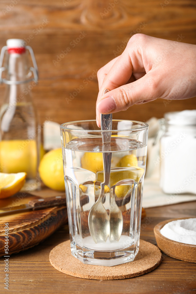 Woman mixing water with baking soda on wooden background Woman mixing water with baking soda on wooden background