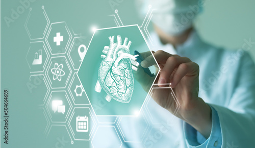Unrecognizable female doctor holding graphic virtual visualization model of  Heart organ in hands. Multiple virtual medical icons. photo