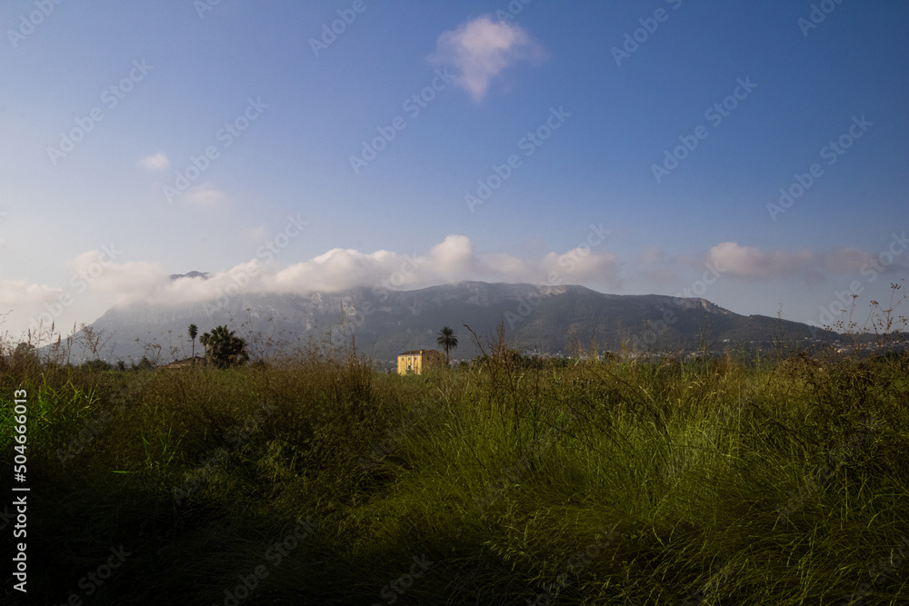yellow house between mountains and field yellow house between mountains and field