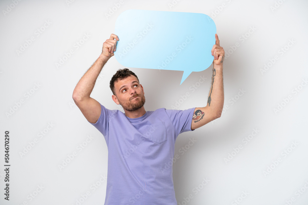 Young Brazilian man isolated on white background holding an empty speech bubble and with sad expression Young Brazilian man isolated on white background holding an empty speech bubble and with sad expression