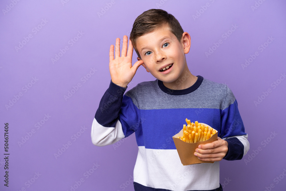 Little boy holding fried chips isolated on purple background listening to something by putting hand on the ear Little boy holding fried chips isolated on purple background listening to something by putting hand on the ear