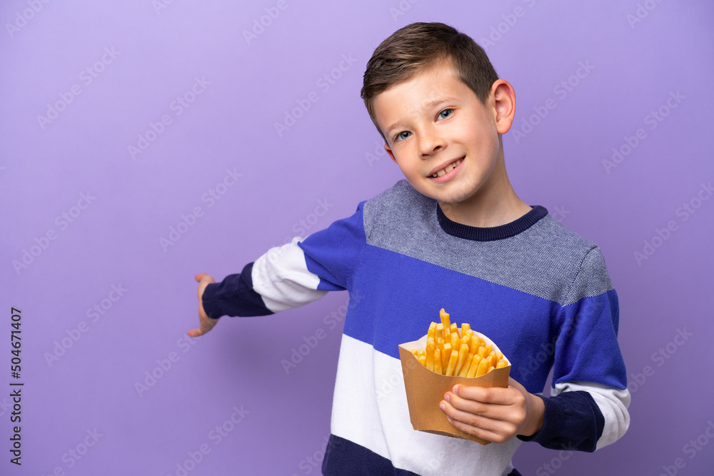 Little boy holding fried chips isolated on purple background extending hands to the side for inviting to come Little boy holding fried chips isolated on purple background extending hands to the side for inviting to come