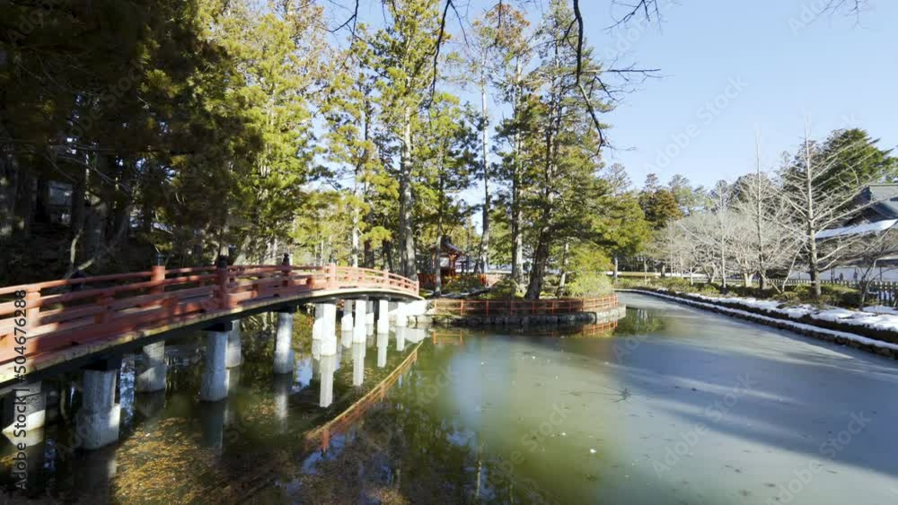 Cinematic gimbal shot of historic bridge over pond at Buddhist temple in Mount Koya in Wakayama prefecture, Japan