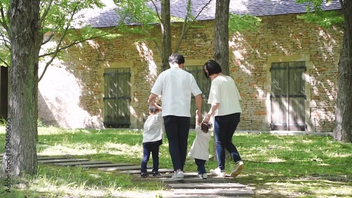 新緑の公園手を繋いで歩く日本人の4人家族