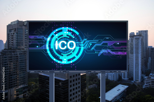 ICO hologram icon on billboard over panorama city view of Bangkok at sunset. The hub of blockchain projects in Southeast Asia. The concept of initial coin offering, decentralized finance