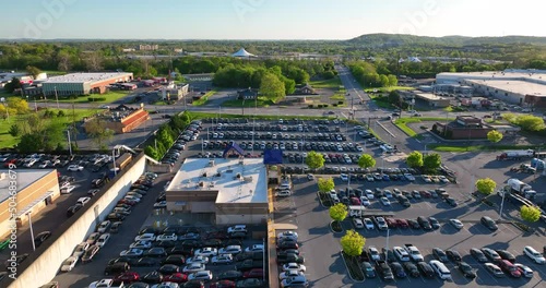 Aerial descending shot of full parking lot. Cars parked at CarMax dealership during golden hour sunset. Low priced used cars. photo