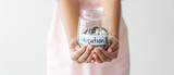 Kid holding her saving coins jar concept of savings money for future education school admission fee. Little daughter learn to save money.
