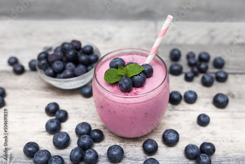 Healthy breakfast of smoothie, dessert, yogurt or milkshake with fresh blueberry on gray, dark wooden table.