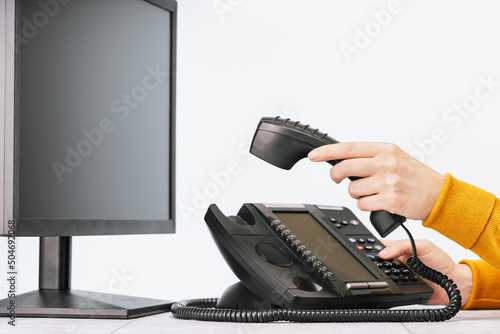 business and communications. Minitor and voip phone in the office, close up of a hand. IP telephony, Cold calling. Audit or accounting. Call center hot line photo