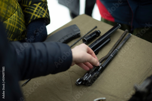 Children learn to shoot in Russia. Assembly of automatic weapons. Lesson in military training. Details of war training.