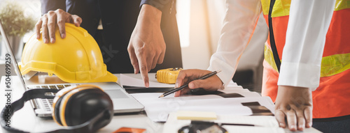 Close up hands of businessman from consultancy service discussing with project contractor and reviewing blueprint for build real estate facilities.