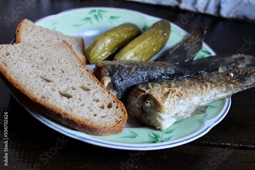 fried fish, pickles and slices of bread on a plate