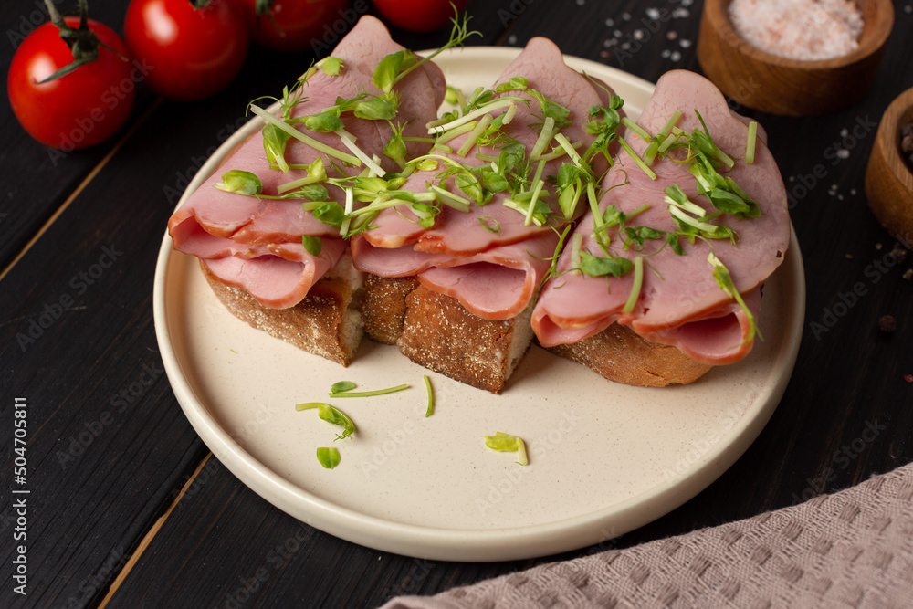 Toast on fresh toasted bread with cream cheese, ham and microgreens, open space Toast on fresh toasted bread with cream cheese, ham and microgreens, open space