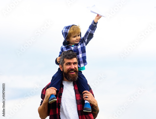 Portrait of happy father giving son piggyback ride on his shoulders. Child play with toy plane. Family travel vacation, father's day.