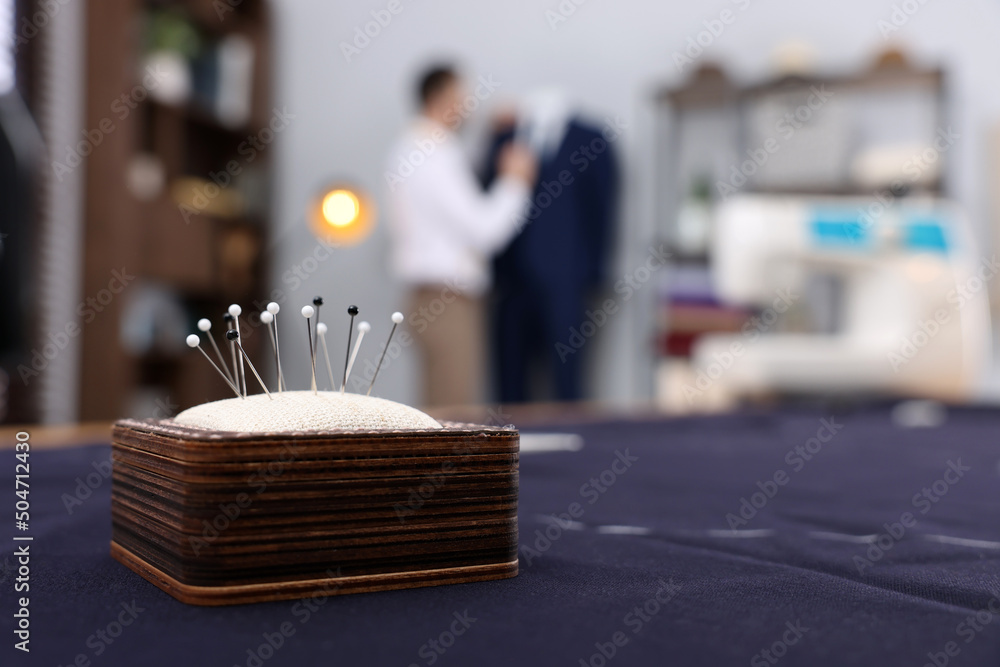 Dressmaker working in atelier, focus on pin cushion. Space for text Dressmaker working in atelier, focus on pin cushion. Space for text