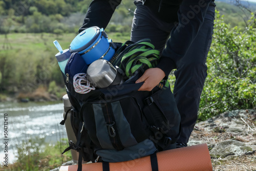 Hiker packing backpack on rocky hill near river, closeup photo