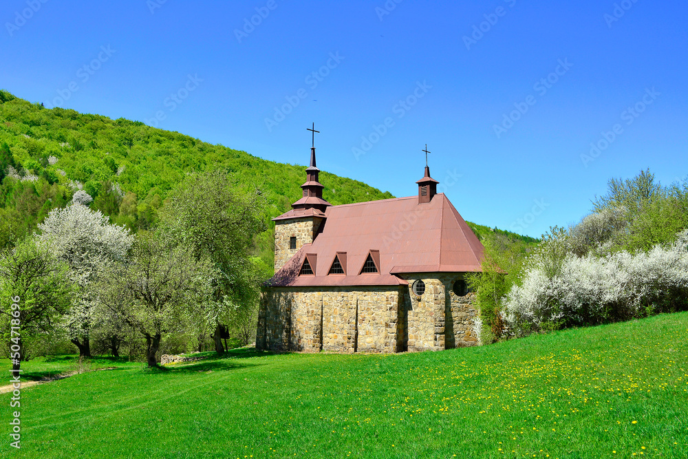 A stone church in the picturesque landscape in Huta Polanska of the Low Beskids (Beskid Niski) in spring sunny day, Poland A stone church in the picturesque landscape in Huta Polanska of the Low Beskids (Beskid Niski) in spring sunny day, Poland