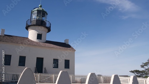 Vintage lighthouse tower, retro light house, old fashioned historic classic white beacon, fresnel lens. Nautical navigational coastal building, picket fence,1855. Point Loma, San Diego, California USA