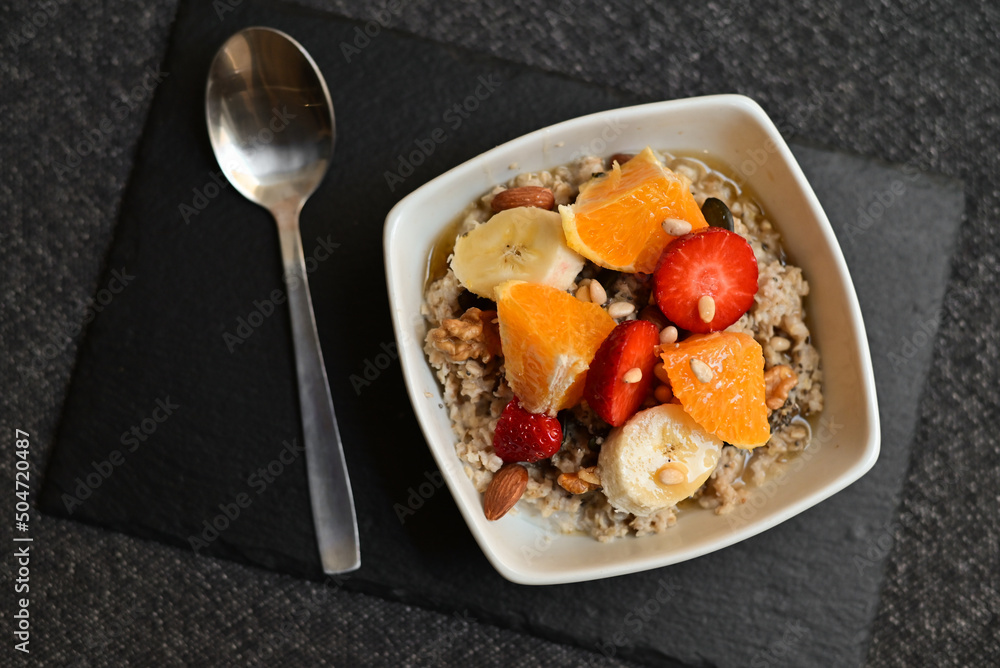 Fruit salad with chia seeds in the white bowl in the center of the black wooden background. Top view. Closeup. Fruit salad with chia seeds in the white bowl in the center of the black wooden background. Top view. Closeup.