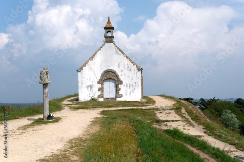 The Saint-Michel tumulus in Carnac, with its chapel and its calvary; under a slightly cloudy blue sky