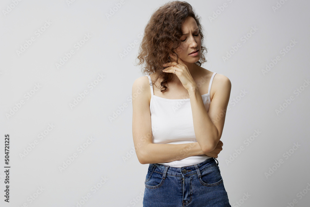 Unhappy sad nervous curly beautiful woman in basic white t-shirt fold hands looks aside thinking about problems posing isolated on over white background. People Emotions Lifestyle concept. Copy space Unhappy sad nervous curly beautiful woman in basic white t-shirt fold hands looks aside thinking about problems posing isolated on over white background. People Emotions Lifestyle concept. Copy space