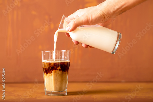 Wallpaper Mural Hand is pouring milk to brewed coffee in studio with copy space. Torontodigital.ca