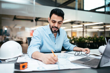 Busy smiling smart attractive millennial muslim male designer with beard working on project in office interior