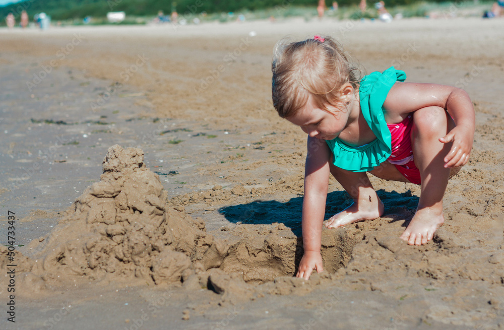 Girl of European appearance having fun on the beach and building sand castles Girl of European appearance having fun on the beach and building sand castles