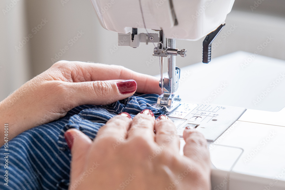 woman hands close up sewing on machine stitching fabric material