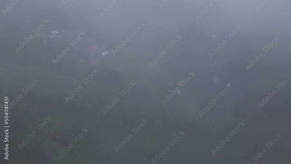 Aerial shot through the clouds with a village behind, surrounded by forest,, in Darjeeling, India Aerial shot through the clouds with a village behind, surrounded by forest,, in Darjeeling, India