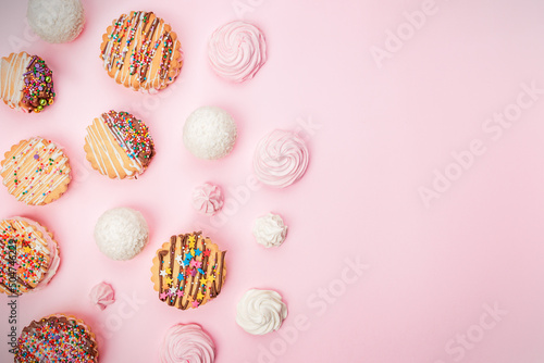 Cakes cookies sandwiches decorated with chocolate and multicolored stars and handmade marshmallows lie on a pink background.