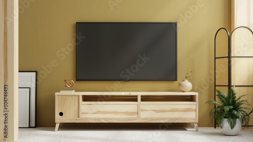 TV on cabinet in modern living room with plant on yellow wall background.