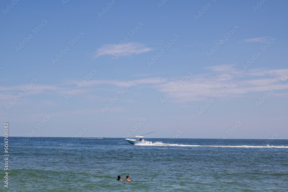 A couple in the water watching a motor boat go by in ocean waters