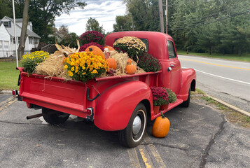 a classic old truck filled with Halloween season flowers hay and festive fall orange pumpkins