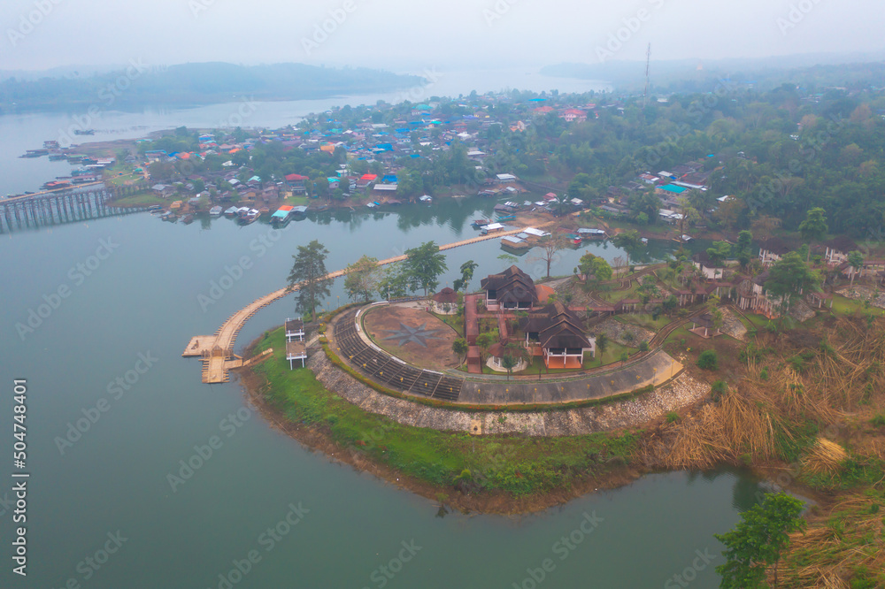 Aerial top view of residential local houses in Mon village, nature trees with lake or river, Kanchanaburi, Thailand in urban city town in Asia, buildings.