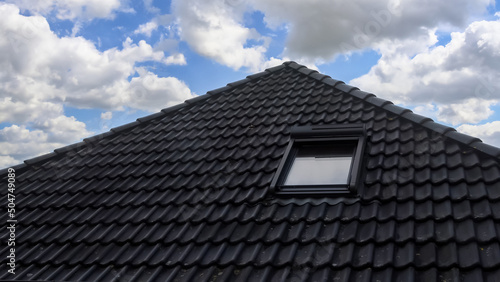 Bilde på lerret Open roof window in velux style with black roof tiles.