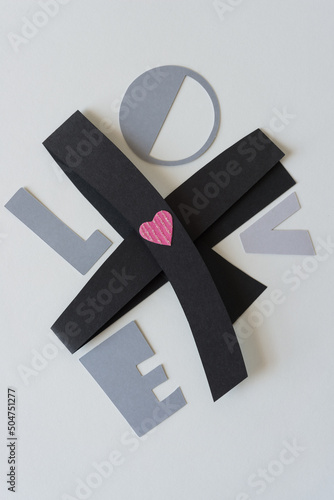 the letters l, o, v, and e, and a pink heart, resting on a black paper objct photo