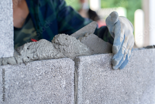 masonry worker make concrete wall by cement block and plaster at construction site