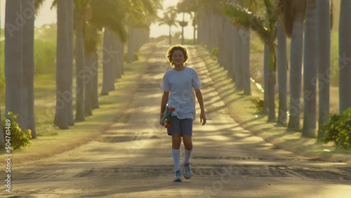 A teenager is skating along a beautiful road with palm trees. Silhouette of a boy with a skateboard