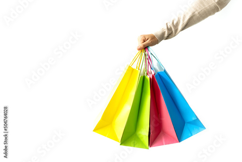 Woman hand holding colorful paper shopping bags on white background with copy space