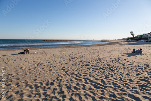 Footprints crossing the sand structures drifted by the wind with people enjoying the sunset at the calm beach of Carnon-Plage near Montpellier, France with family friendly waterside vacation rentals