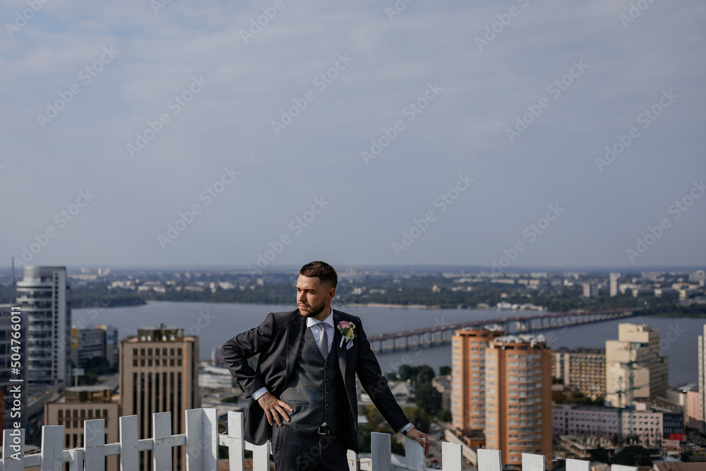City view. High skyscrapers and a bridge across the river. Business center. Stylish and the adorable groom on the roof of the house. Beautiful view