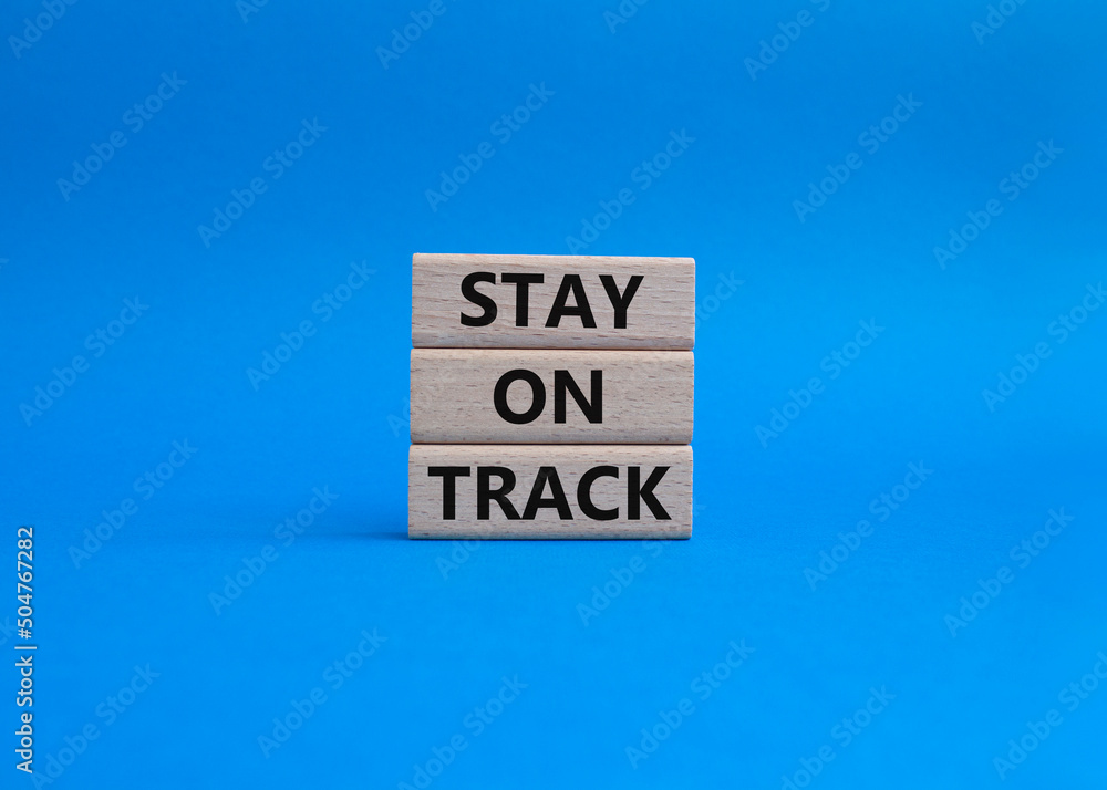 Stay on track symbol. Wooden blocks with words 'Stay on track'. Beautiful blue background. Business and 'Stay on track' concept. Copy space. Stay on track symbol. Wooden blocks with words 'Stay on track'. Beautiful blue background. Business and 'Stay on track' concept. Copy space.
