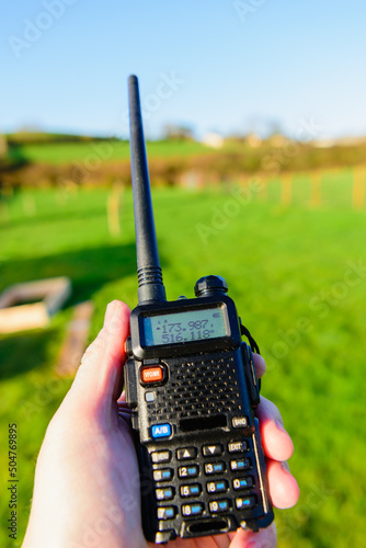 Person holds a small amateur radio transceiver, commonly used within the prepper community for emergency communications. photo