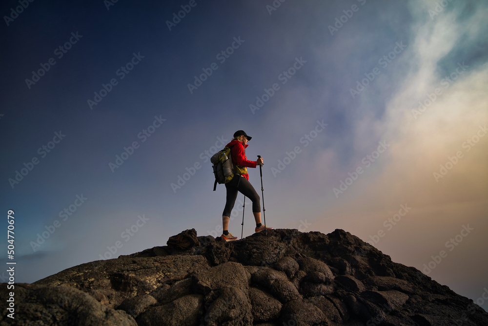 woman with a backpack and red jacket on the top in the mountains 