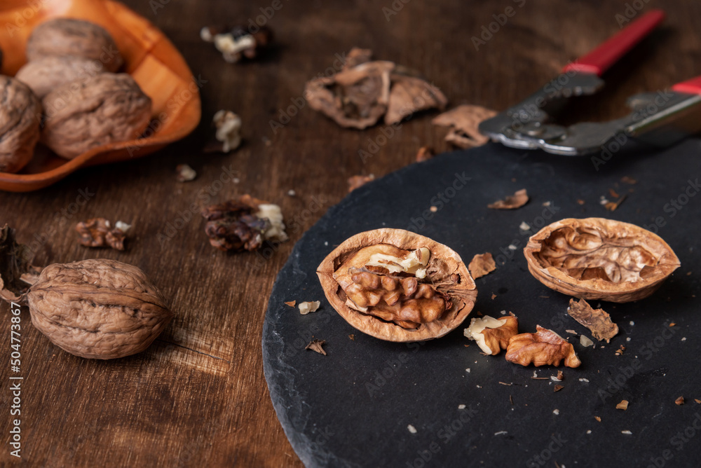 Walnuts on a stone plate next to a nutcracker. Close-up. Walnuts on a stone plate next to a nutcracker. Close-up.