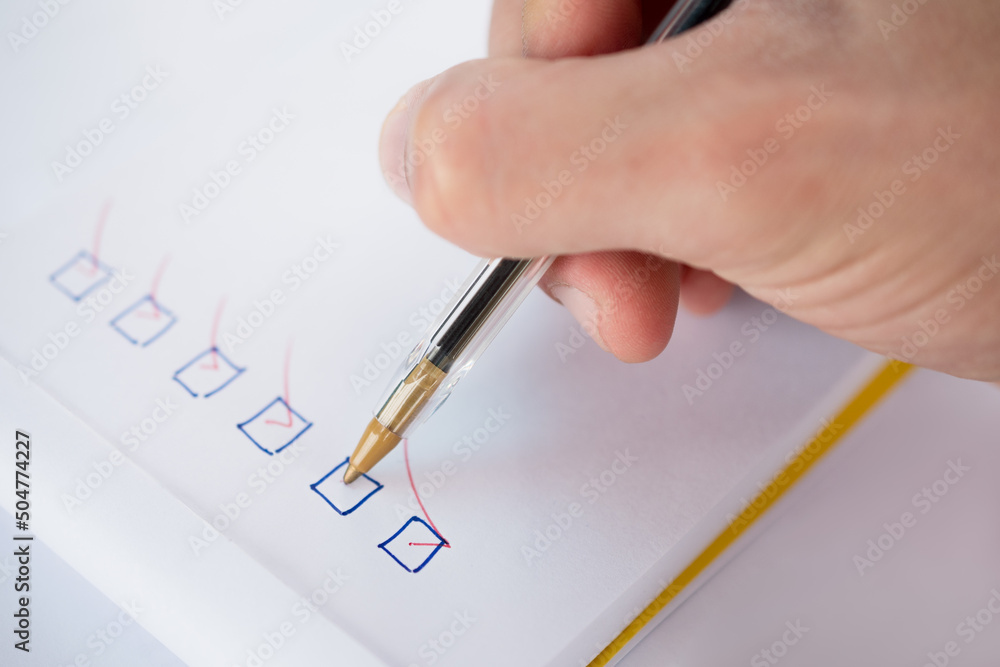 Close-up of a person's hand marking checklist Close-up of a person's hand marking checklist