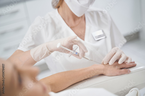 Beauty doctor doing injection into woman arm