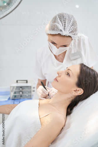 Doctor performing laser mole removal procedure in beauty center