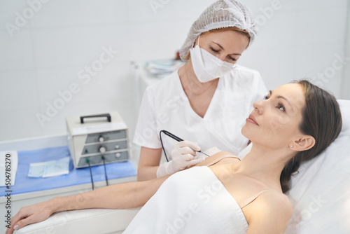 Doctor performing laser mole removal procedure in beauty clinic